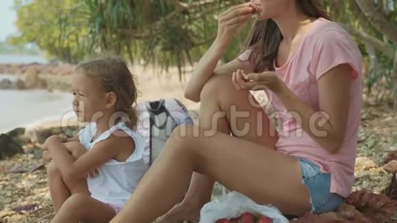 一家人坐在热带海滩上慢动作地吃水果视频的预览图