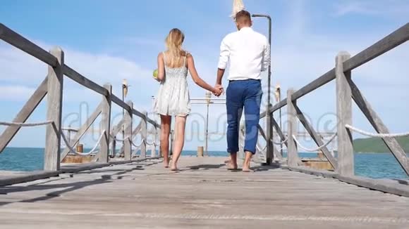 年轻的幸福夫妇在蓝天背景上的木墩上行走浪漫的概念高清1920x1080视频的预览图