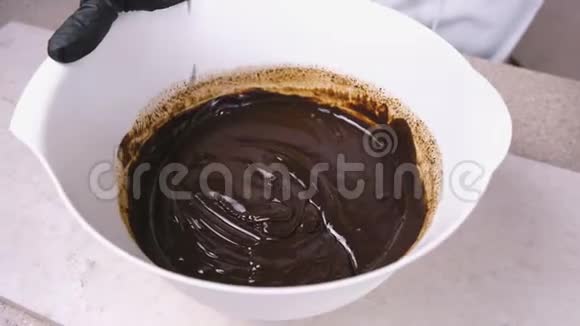 将液体黑巧克力与搅拌机混合在白色碗中特写镜头视频的预览图