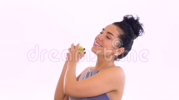 美丽的黑发女人抛出绿苹果嘲笑白色背景视频的预览图