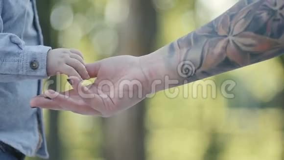 女人手在纹身里抚摸着小男孩手视频的预览图