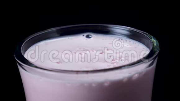 加草莓奶昔的杯子框架新鲜的粉红色奶昔在透明的玻璃黑色隔离视频的预览图