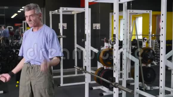 老年人在健身房背景下展示自己的手臂二头肌视频的预览图
