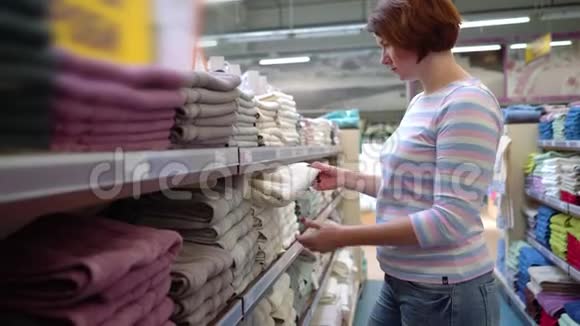 在商店货架旁选择毛巾的白人妇女视频的预览图