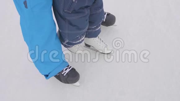 幼儿在溜冰鞋上的第一步爸爸教孩子滑冰握住他的手家庭和室外视频的预览图
