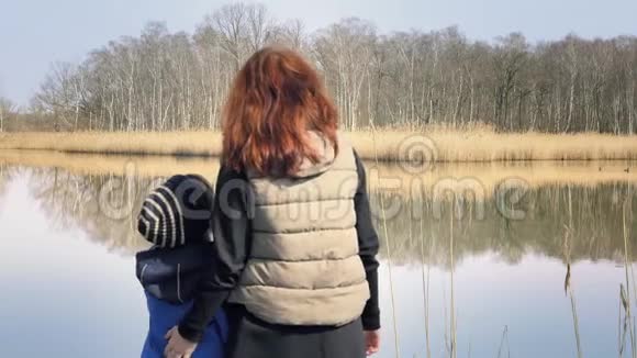 母亲和儿子站在美丽池塘的码头上视频的预览图
