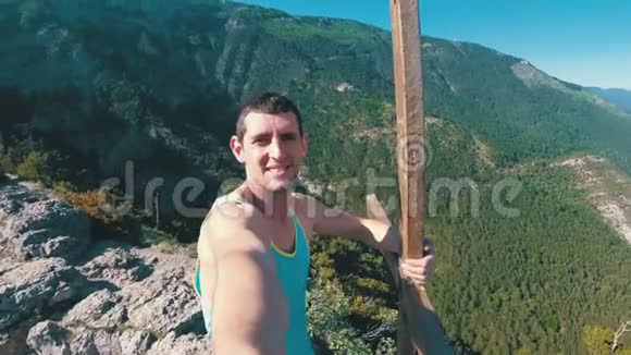在一座岩石山的山顶上一个人带着十字架的微笑喜悦和旋转的相机视频的预览图