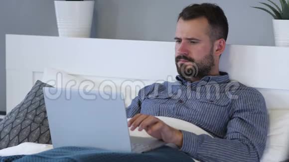 伤心人在床上使用笔记本电脑的失落反应视频的预览图