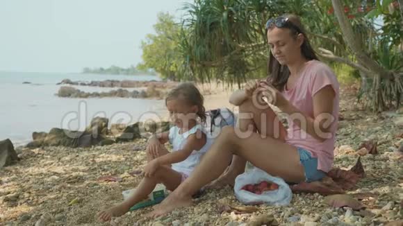 一家人坐在热带海滩上慢动作地吃水果视频的预览图