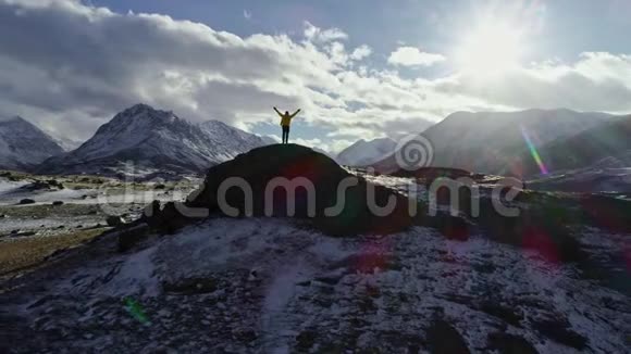 攀登雪峰的男子用冰锥举起双手登山者举起双手站在岩石的顶端视频的预览图