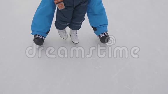 幼儿在溜冰鞋上的第一步爸爸教孩子滑冰握住他的手家庭和室外视频的预览图