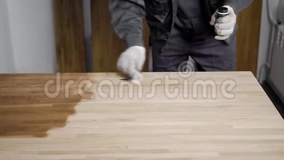 戴手套的人用手在木制面板上涂油视频的预览图