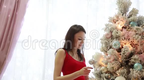 美丽的女孩在室内装饰一棵圣诞树视频的预览图