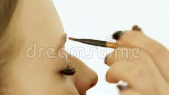 在美容工作室化妆眉毛时闭上女人的脸女人用化妆刷在眉毛上着色视频的预览图