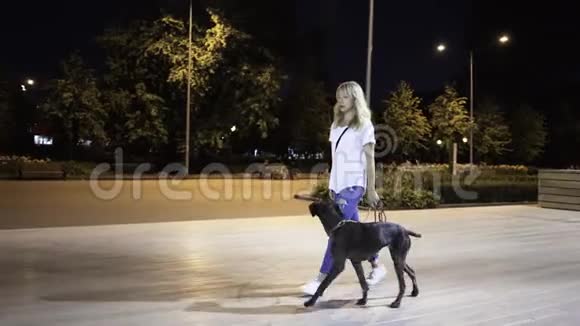 年轻的金发女人训练她的狗和她一起散步视频的预览图
