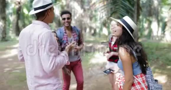 携带背包的人群使用智能手机交谈男人和女人在热带棕榈树的旅行中欢笑视频的预览图