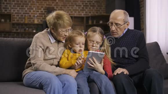 一家人在家里的沙发上使用平板电脑视频的预览图