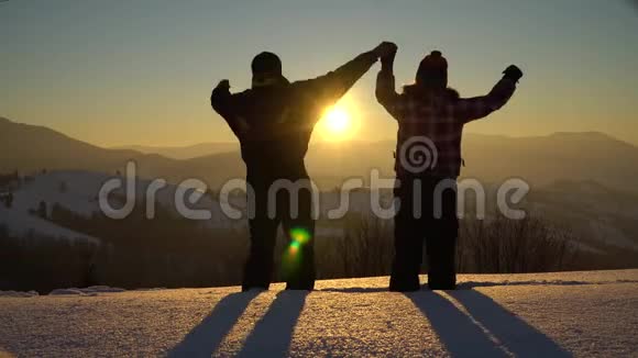 冬天一个男人和一个女人在白雪覆盖的山上游来游去他们高兴地跳起来牵着手在里面视频的预览图