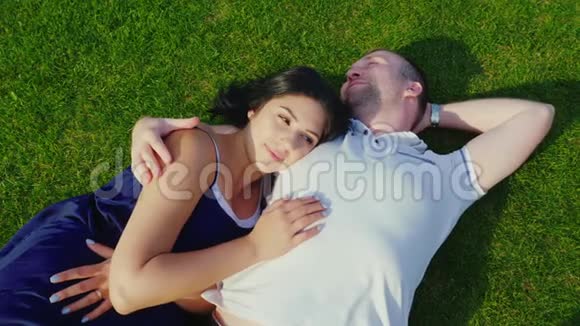 俯视图一个有怀孕妻子的男人躺在绿草上视频的预览图