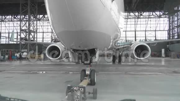 一架客机在机场机库后撤飞机机头起落架和拖运车关闭视频的预览图
