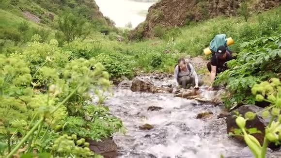 两个游客喝着小溪里干净的水视频的预览图