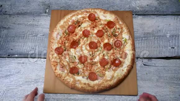 白色桌子背景上木制托盘上的美味披萨框架男人在木制托盘上用意大利辣香肠移动刚出炉的披萨视频的预览图