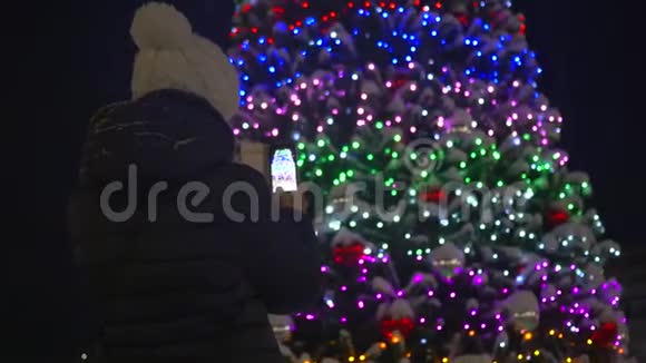 一个女孩正在公园的圣诞装饰背景上拍照视频的预览图