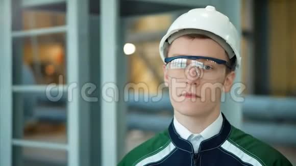 年轻工程师戴着防护头盔在现代化工厂里摆着相机视频的预览图