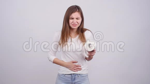 灰色背景下肚子疼的年轻女子视频的预览图