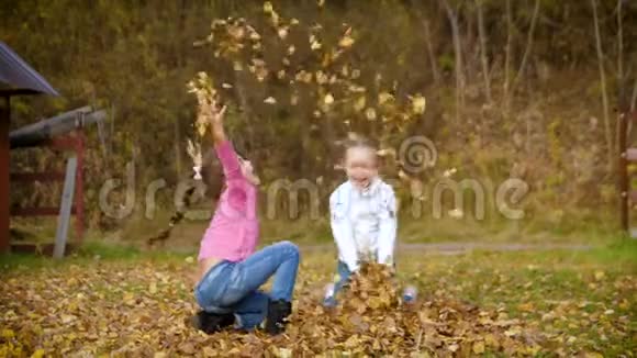 两个小女孩扔秋叶孩子们在秋天的花园里玩耍落叶秋天的户外乐趣4k60fps视频的预览图