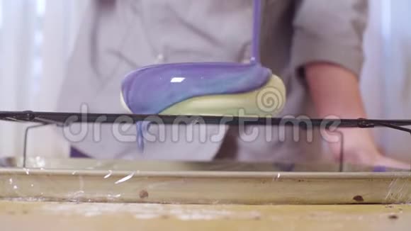 糕点厨师的手在一个大蛋糕上浇上多色镜面釉视频的预览图