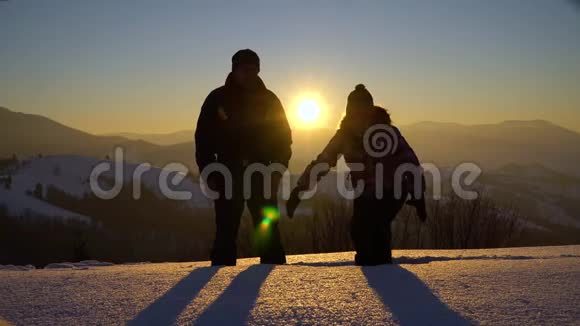 两个年轻的游客站在山上的雪地里手牵着手兴高采烈地把雪扔上来男人和女人在里面视频的预览图