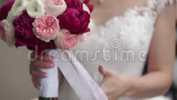 新娘捧着一束白色粉红色和红色的玫瑰摇摆的丝带户外活动缓慢视频的预览图