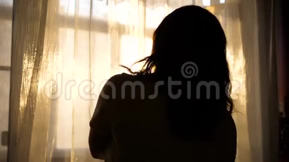 一个年轻的女孩来到窗口戴上耳机听音乐女孩喜欢带耳机的音乐视频的预览图
