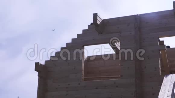 建筑框架木制原木屋在蓝天背景下与一架飞机飞走在建工程a视频的预览图