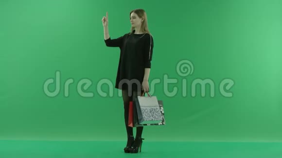 有吸引力的年轻女性在增强现实后用袋子购物彩色钥匙绿色背景视频的预览图