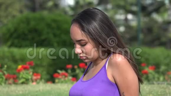 严肃的少女坐在公园里视频的预览图