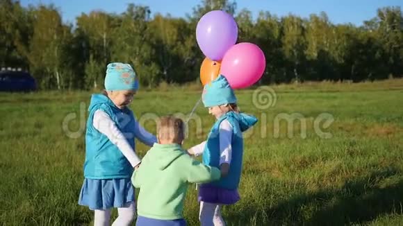 快乐的孩子们拿着气球在公园里手拉手盘旋孩子们露天度假视频的预览图