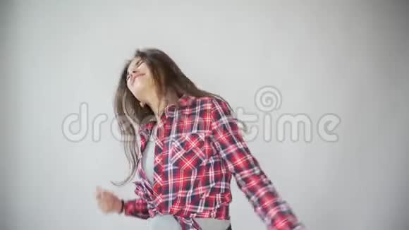 穿着浅灰色背景格子衬衫跳舞的时髦女孩视频的预览图