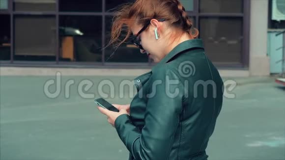 年轻女子在街上打字发手机短信在城市里散步视频的预览图