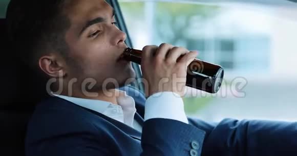 年轻的商人在车里喝啤酒坏消息由于坏交易或坏消息而心情不好的人喝醉了开车视频的预览图
