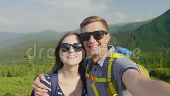 几个游客自己拍照对着镜头微笑在一座风景如画的山的背景下视频的预览图