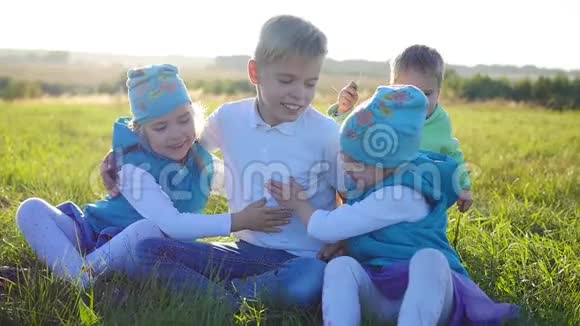 孩子们坐在公园的草坪上笑拥抱和微笑孩子们露天度假视频的预览图