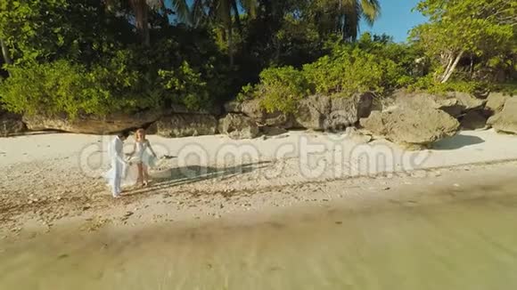 新婚夫妇很高兴跑进大海鸟瞰博霍尔海岸岛空中飞行菲律宾视频的预览图