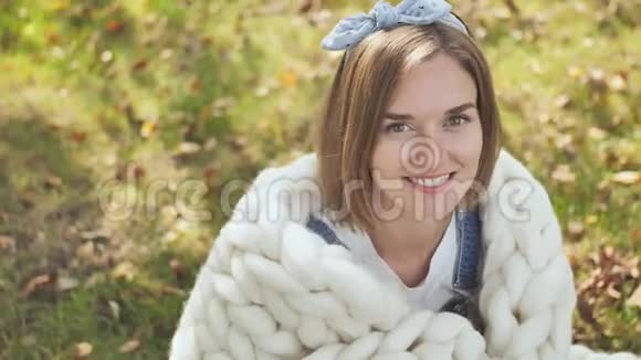 初秋一个微笑的女孩裹在一个梅里诺格子里视频的预览图