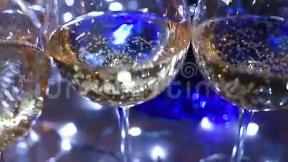 在圣诞灯光背景下的桌子上放着香槟或葡萄酒的漂亮眼镜视频的预览图