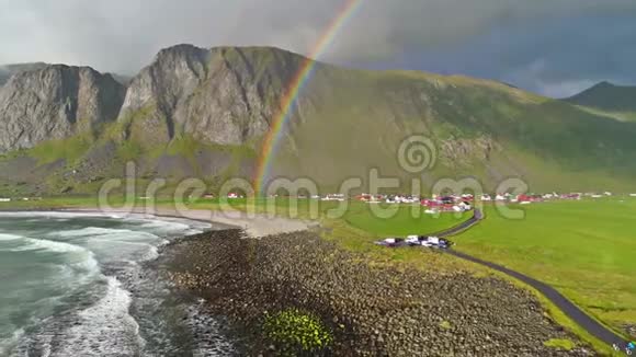美丽的彩虹在蓝色的海浪冲击石滩在乡村山岗村4k空中无人机景观视频的预览图