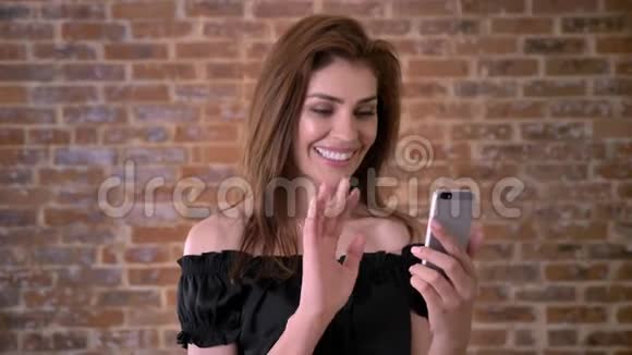女人有智能手机视频通话沟通概念砖背景视频的预览图