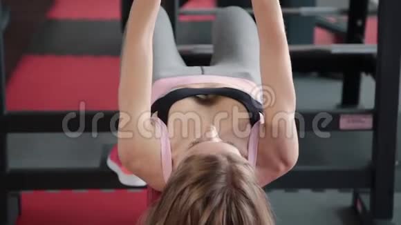 美丽的运动年轻女孩哑铃在健身房锻炼胸肌视频的预览图