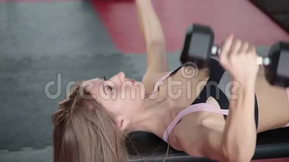 美丽的运动年轻女孩哑铃在健身房锻炼胸肌视频的预览图